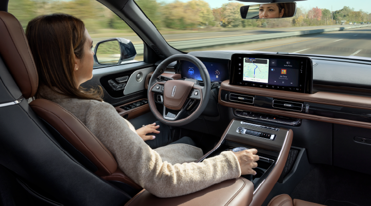 A woman is seen sitting in the driver’s seat of her 2025 Lincoln Aviator® SUV with her hands off the steering wheel. | North Park Lincoln in San Antonio TX