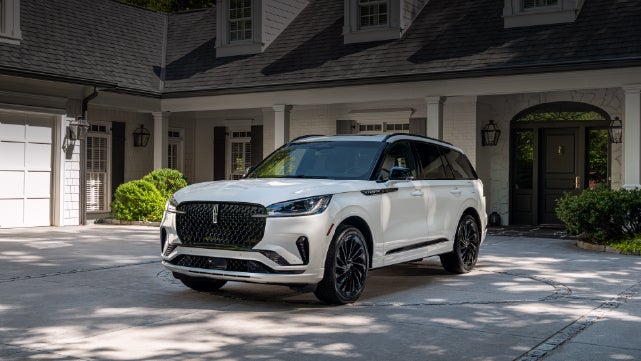 A white 2026 Lincoln Aviator® SUV is parked in the driveway of a luxury home. | North Park Lincoln in San Antonio TX