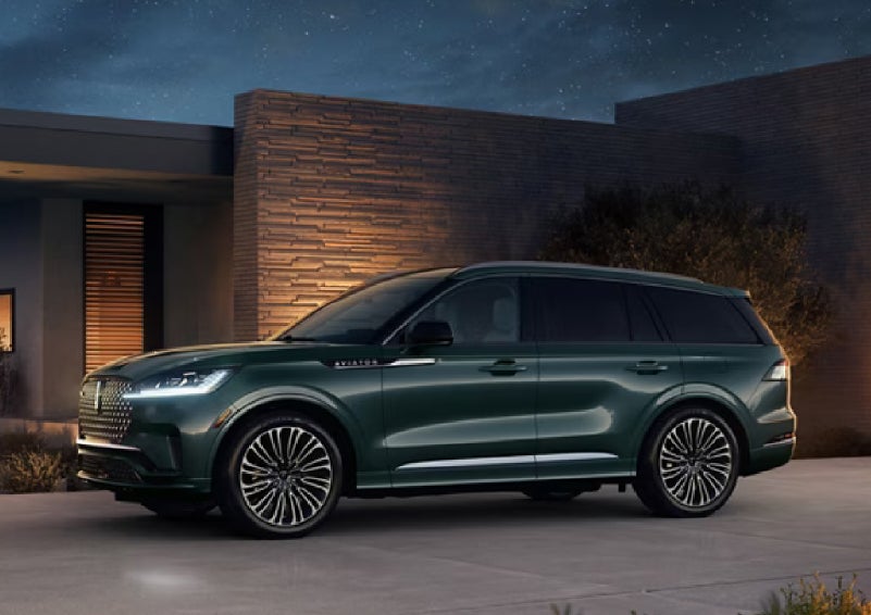 A green 2027 Lincoln Aviator® SUV is parked outside a contemporary home. | North Park Lincoln in San Antonio TX