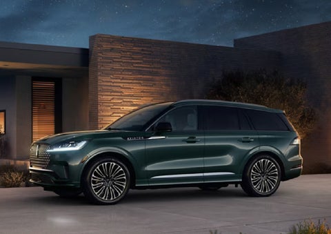 A green 2027 Lincoln Aviator® SUV is parked outside a contemporary home. | North Park Lincoln in San Antonio TX
