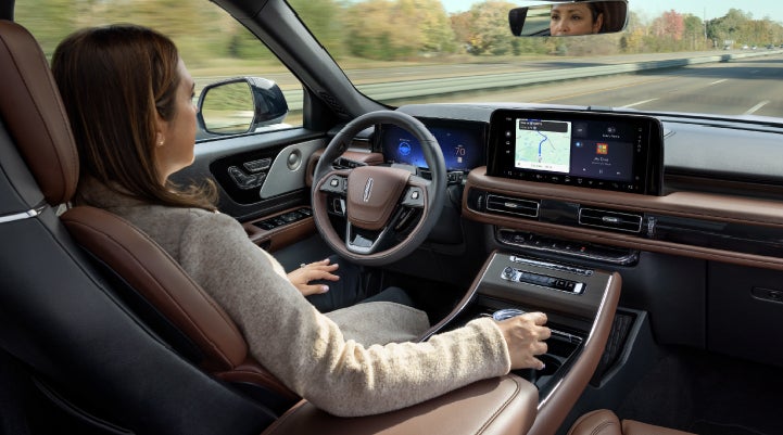 A 2027 Lincoln Aviator® SUV is being driven hands-free on a highway lined with trees. | North Park Lincoln in San Antonio TX