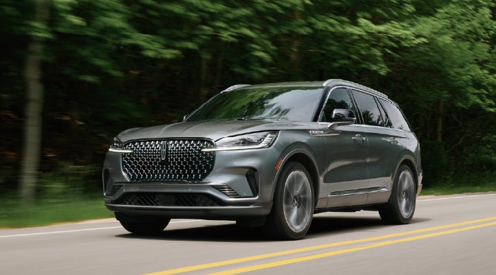 A 2027 Lincoln Aviator® SUV is being driven down a road lined with trees. | North Park Lincoln in San Antonio TX
