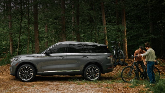 A father and son load e-bikes on a bike rack attached to a 2027 Lincoln Aviator® SUV. | North Park Lincoln in San Antonio TX